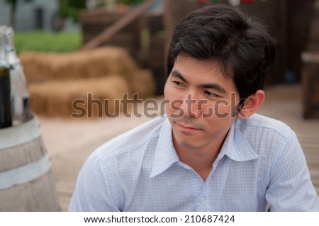 An asian man with white shirt looks something with the country background