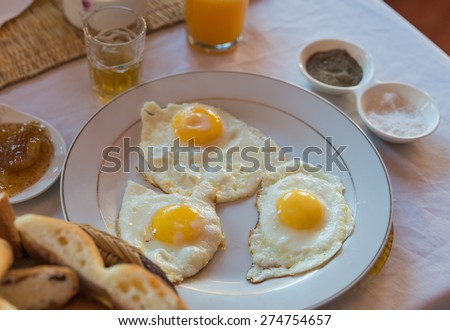 Three fried eggs on white plate for breakfast with mint tea which is the traditional tea of Moroccan
