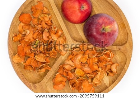 Dried thin slices of apples and two whole fresh red apples on the wooden compartmental dish on a white background, fragment top view 商業照片 © 