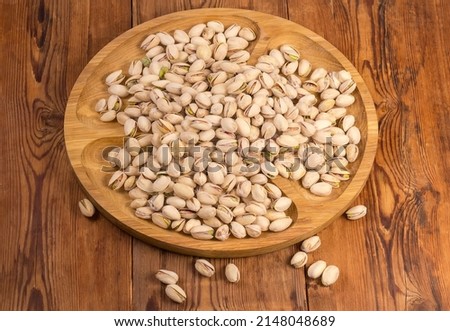 Roasted salted pistachio nuts with partly open shells on a wooden compartmental dish on the old rustic table 商業照片 © 