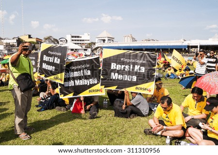 KUCHING, MALAYSIA - AUGUST 29, 2015: Crowds sitting on ground and carrying banners at the Bersih 4 rally in Song Kheng Hai rugby field, Kuching, Sarawak.