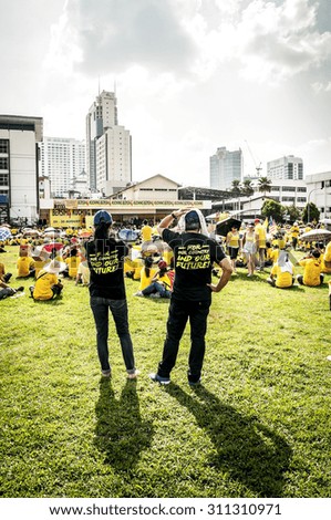 KUCHING, MALAYSIA - AUGUST 29, 2015: A couple standing behind the crowds at Bersih 4 rally in Song Kheng Hai rugby ground, Kuching, Sarawak.