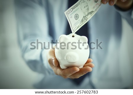 Businessman putting  money into a piggy bank isolated on white background
