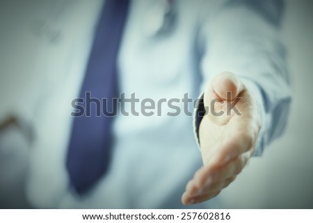 Male doctor extending his hand for a handshake in clinic