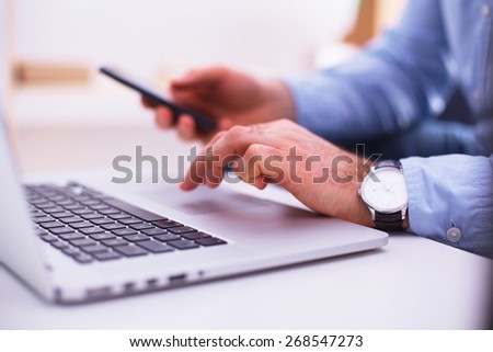 Businessman using laptop and mobile phone