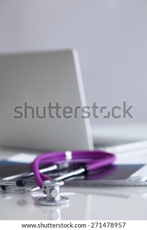 Violet stethoscope near laptop computer