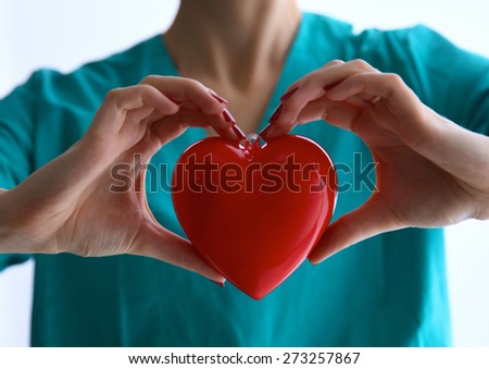 Female doctor with stethoscope holding heart over white background.