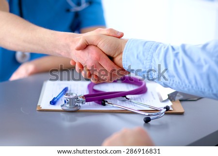a patient's hand shaking a doctor's hand
