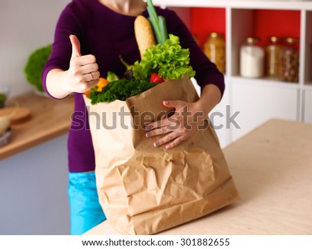 Assorted fruits and vegetables in brown grocery bag holding a young girl