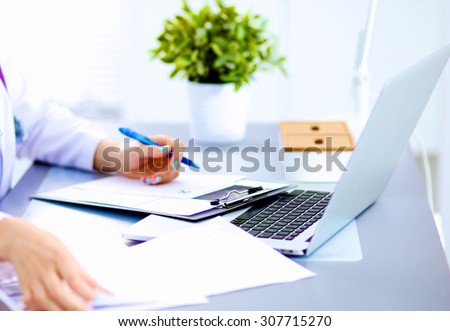 Portrait of young woman doctor in white coat at computer