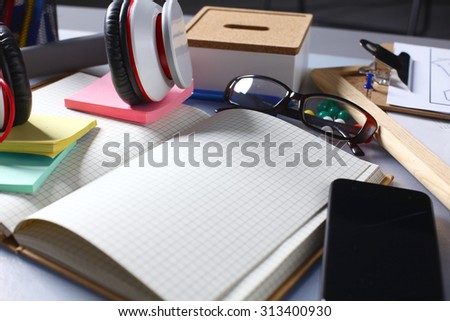 Mix of office supplies and gadgets on a wooden desk background. View from above