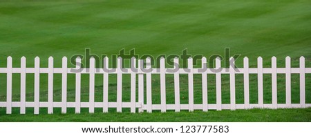 Green lawn and white wood fence