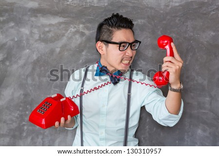 Young man looking the red telephone with angry face
