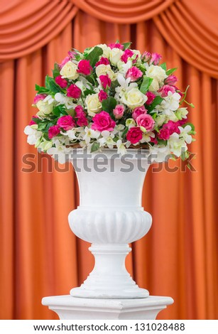 Bouquet of flowers in old fashion vase isolated on red curtain