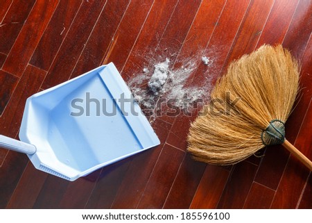 Close up dirty dust on old wooden parquet floor with broom and dustpan