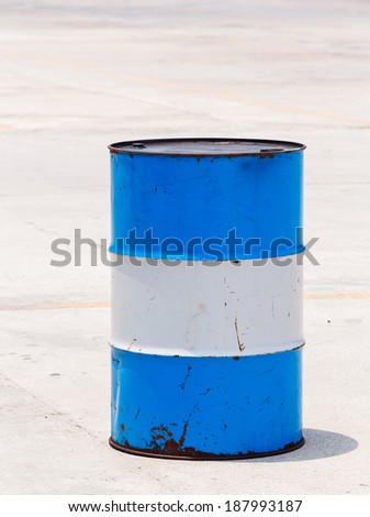 Old and dirty oil barrel tank isolated on concrete floor in bright sunlight
