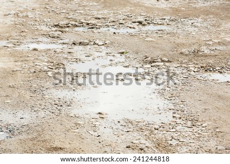 Close up bumpy stone road with water in potholes