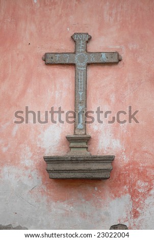 The stone cross in pink wall in Antigua.