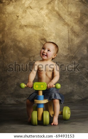 A little blonde girl sitting on a toy bike