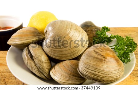 Bowl of cherrystones (quahogs, or hard-shell clams) with lemon, parsley and cocktail sauce on old cutting board