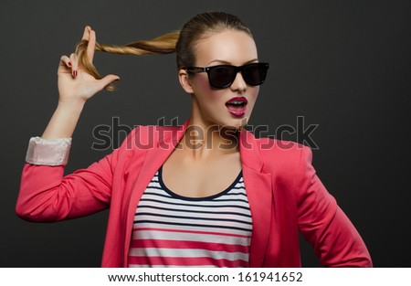 Beautiful girl in sunglasses holds the own hair and twists them and talking