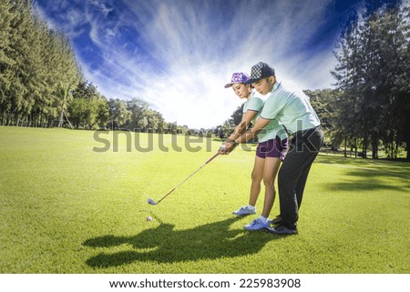 Young female golf player at Driving Range with a Golf Pro, she presumably does exercise
