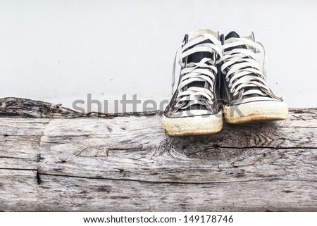 black sneakers on the old Log wood  and gray concrete walls