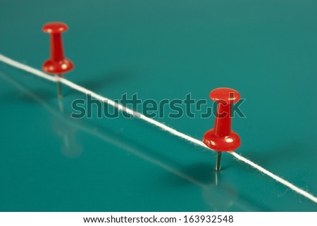 thumbtacks red and white wire on green background