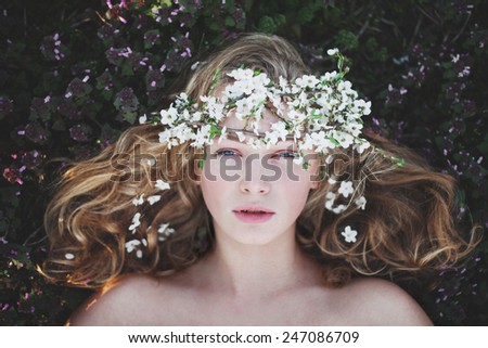mysterious beautiful girl with flowers in her hair. Queen blooming gardens. Fields of flowers