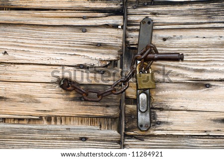 Old wooden gate locked with chain and padlock to handle