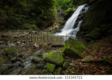 beautiful waterfall in dark mysterious forest