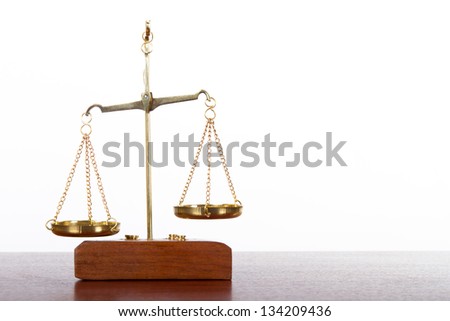 Golden balance scales of justice on wooden table, isolated on white background.