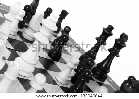 Black and white chess pieces on board, isolated on white background.