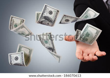 One hundred dollar money banknotes flying and falling on young business woman hand.