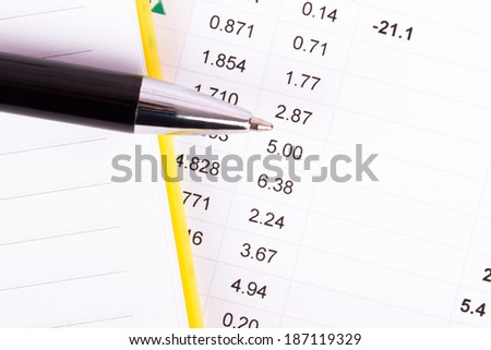 Financial data analysis with notebook and pen, top view.