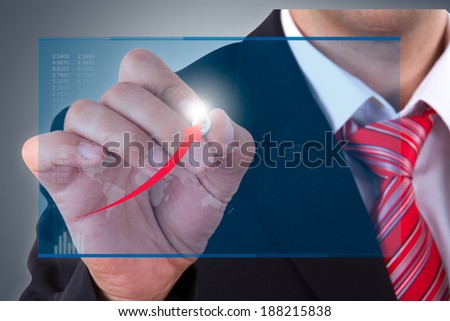 Businessman holding pen and writing on digital screen financial statistics.
