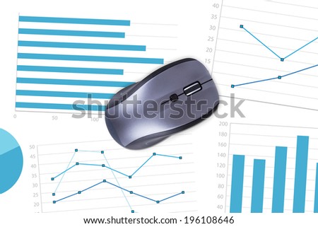Top view of wireless computer mouse on paper sheet with financial statistic charts.