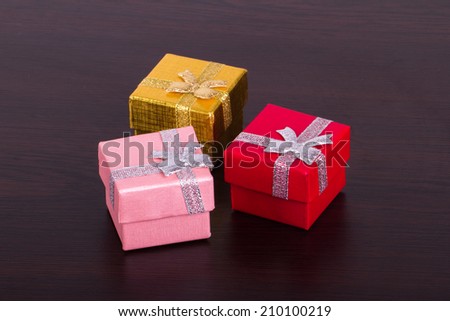 Three colorful gift boxes on wooden table.