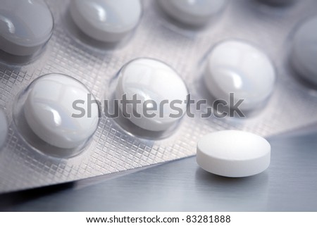 Blister pack of round white pills. One is out of the package.