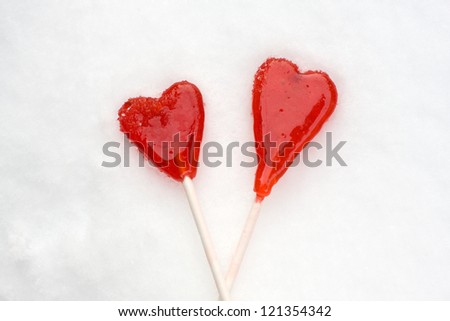 Two heart shape red lollipops on the snow, hand made