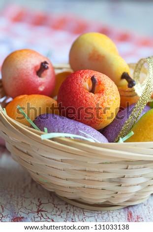 Fruit shaped candies in macro image of marzipan sweets in a basket on the wooden table, close-up