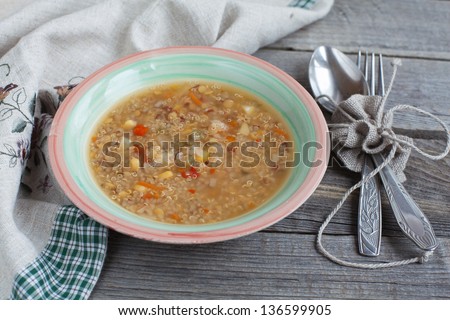 Vegetarian soup with quinoa, rice red, yellow lentils, corn, peppers, carrots, onions and celery on the wooden table in rustic style