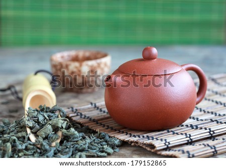 Traditional chinese tea ceremony accessories: tea pot, cup and green tea on the wooden table, selective focus