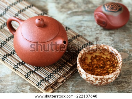 Traditional chinese tea ceremony accessories: tea pot, cup, green tea and clay turtle on the wooden table, selective focus on pot. Toned