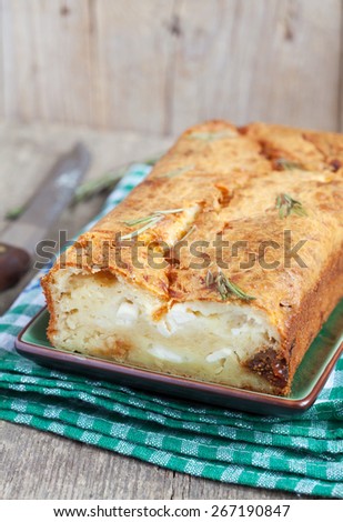 Savory loaf cake with parmesan cheese, feta cheese, figs and dry rosemary on a wooden table in rustic style. Selective focus.