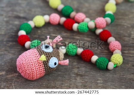 Necklace made from knitted beads for the baby sitting in a sling in front of his mother. Selective focus.