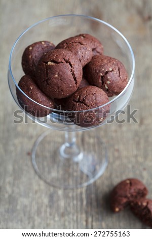 Italian chocolate cookies with walnuts in a wine glass on a wooden table, rustic style, selective focus