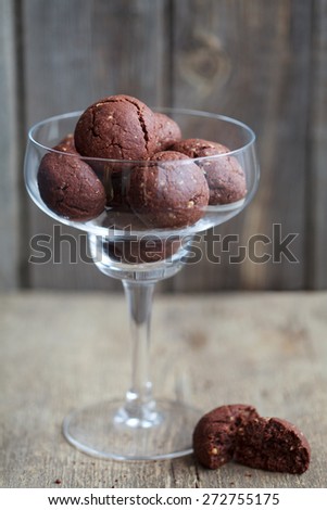 Italian chocolate cookies with walnuts in a wine glass on a wooden table, rustic style, selective focus