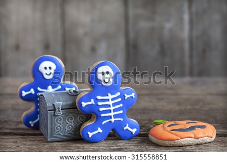 Homemade gingerbread cookies in the form as Halloween skeletons, jack-o-lantern pumpkin and bats on the wooden table. Space for text and selective focus.