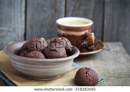 Italian chocolate cookies with walnuts and a cup of coffee on a wooden table, rustic style, selective focus